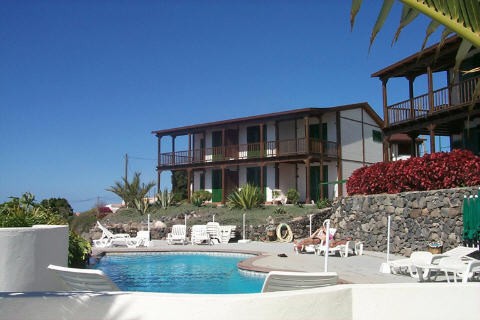 La piscina, con los jardines y apartamentos al fondo de la imagen